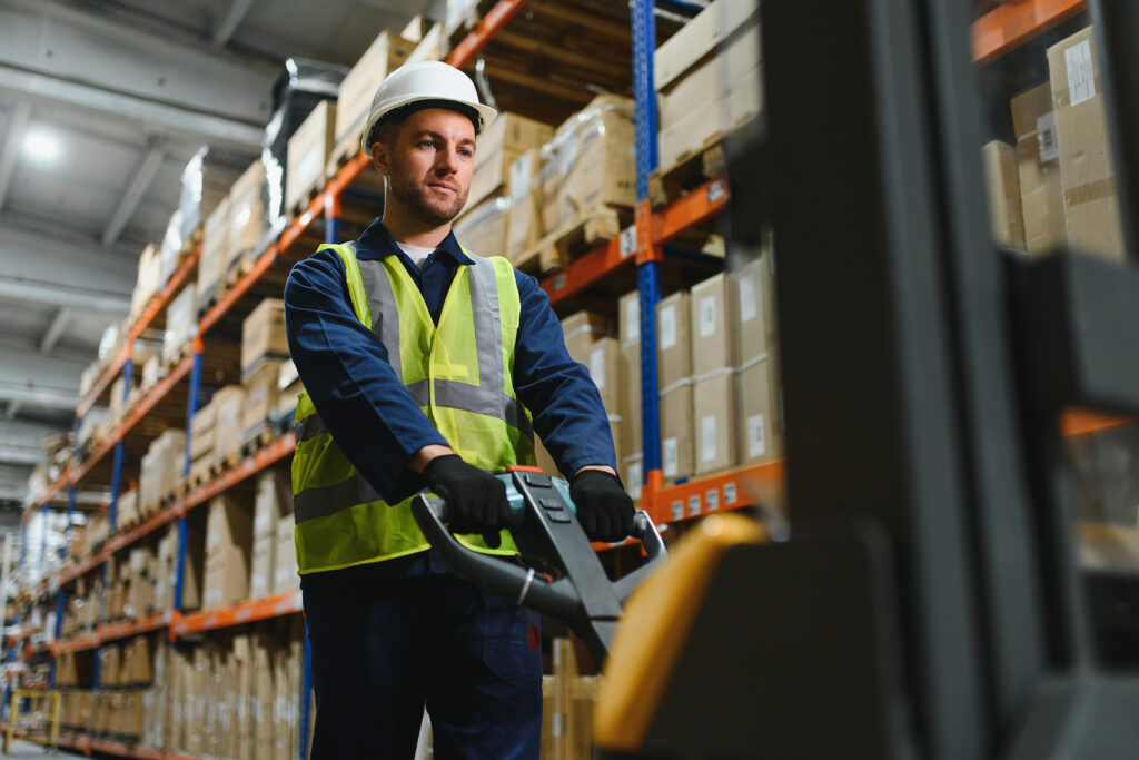 a male worker using one of the best pallet trucks to move loads in a warehouse