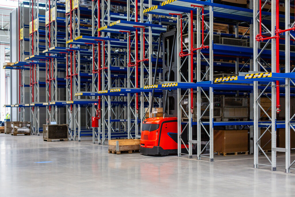 a vna forklift in between the aisle of an industrial warehouse rack