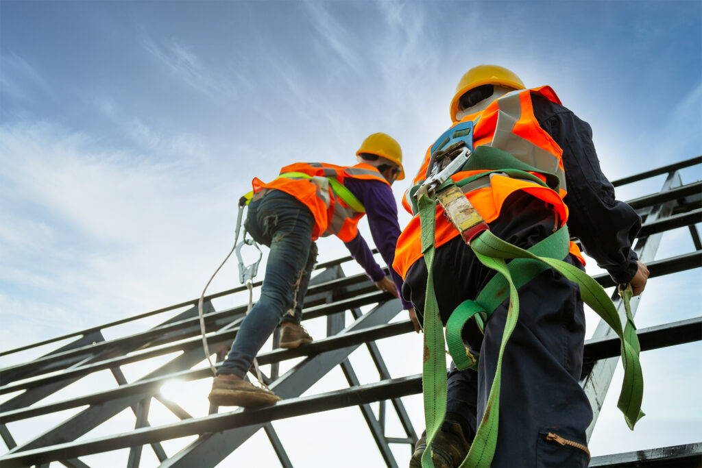 two roofers working at height using a safety body harness on the roof structure