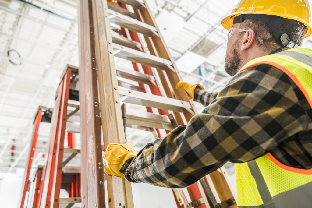 a warehouse worker wearing PPE as they hold a ladder as per the guidance from the working at height regulations
