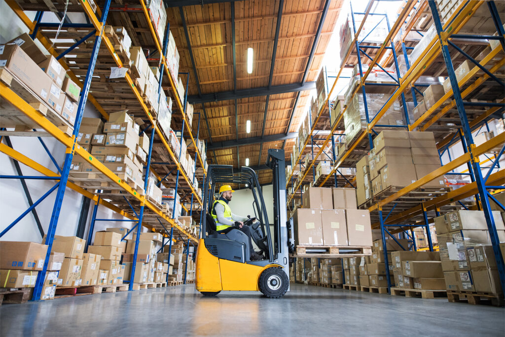 a worker lifting boxes onto warehouse racking using a powerful type of forklift truck