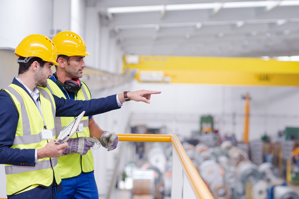 an inspector and site manager discussing health and safety in the warehouse from an elevated platform overlooking the fascilities