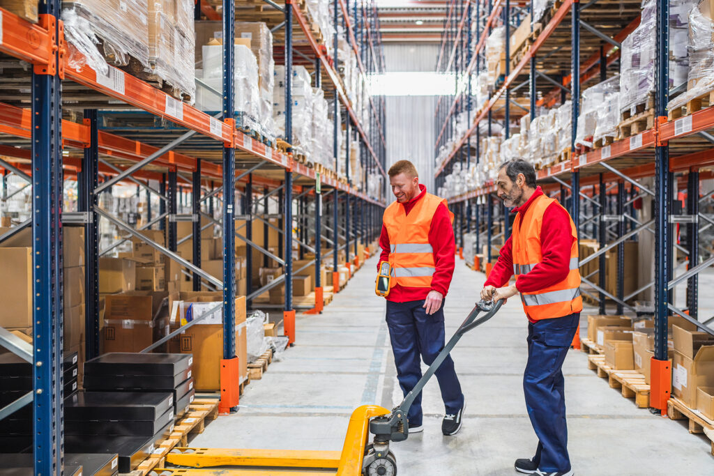 two warehouse staff safely working side by side with a manual pallet truck