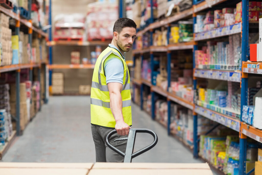 a worker on the warehouse floor using a pallet truck for manual handling activities