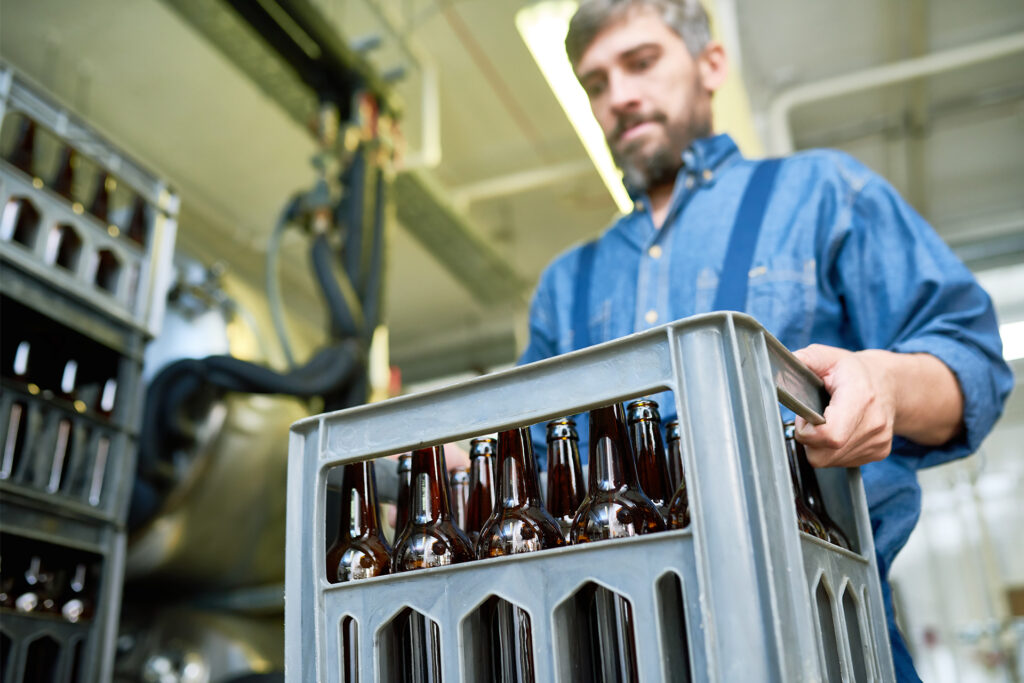 a bartender in a basement carrying heavy crates of bottles