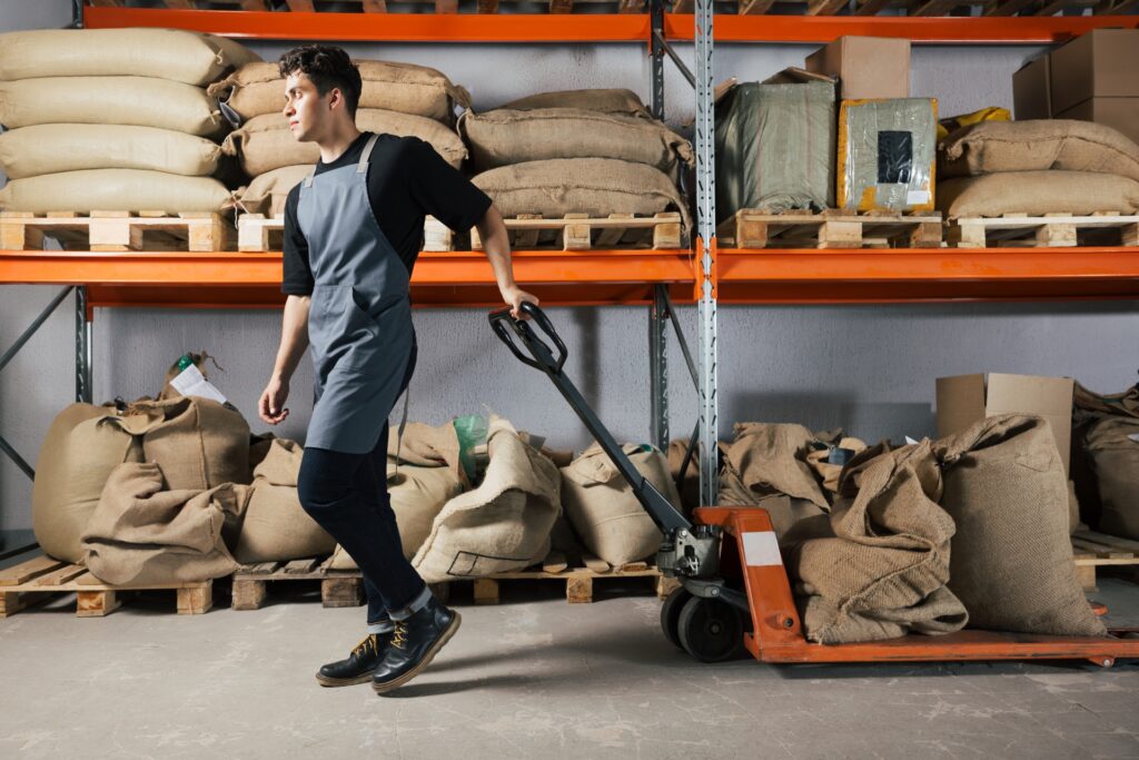a worker in a large stockroom using a pallet truck safely