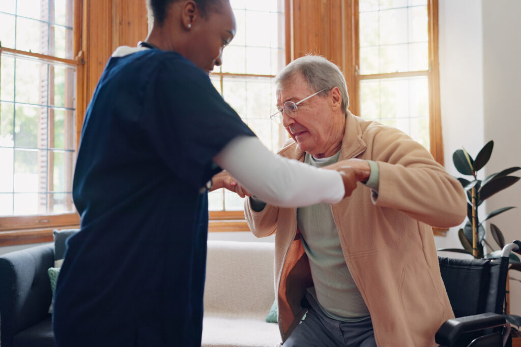 a carer supporting an elderly man out of a wheelchair