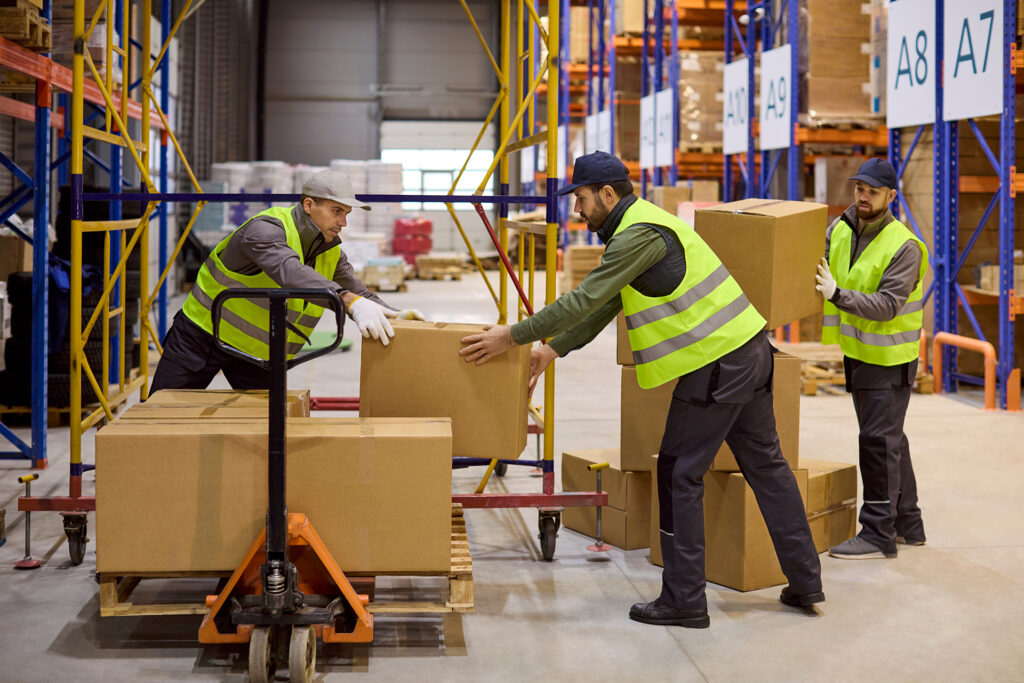 warehouse staff in high-vis loading cardboard boxes onto a pallet truck