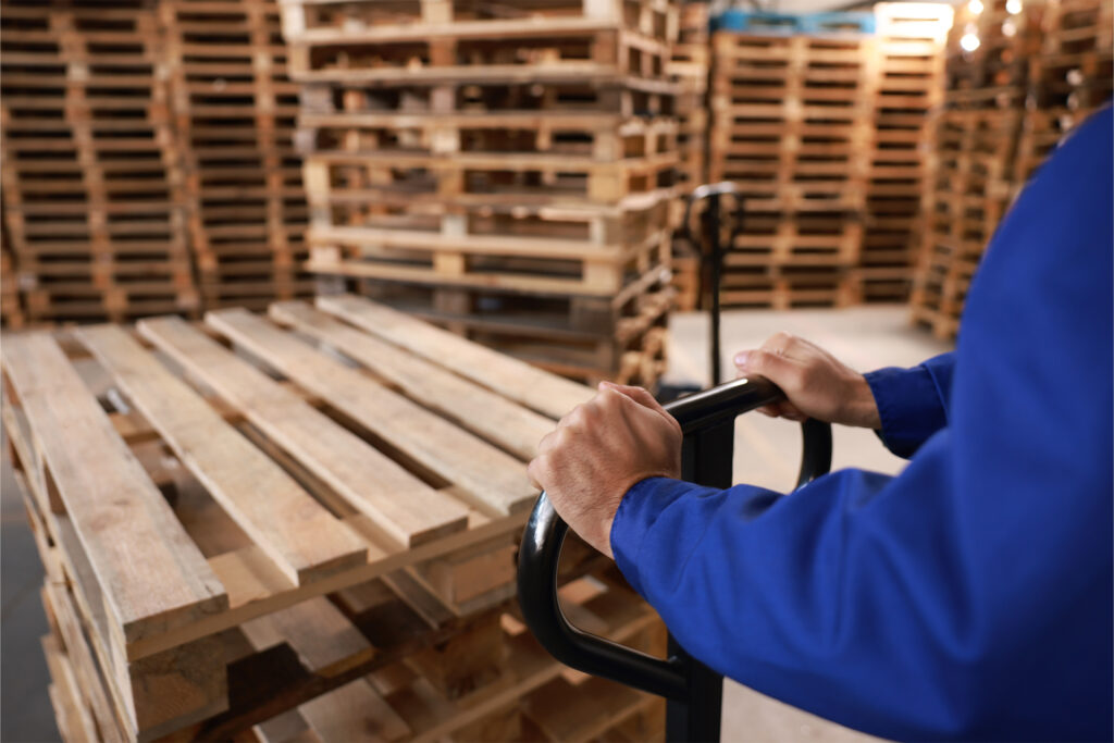 a materials handling specialist using a pallet truck to stack different sized pallets